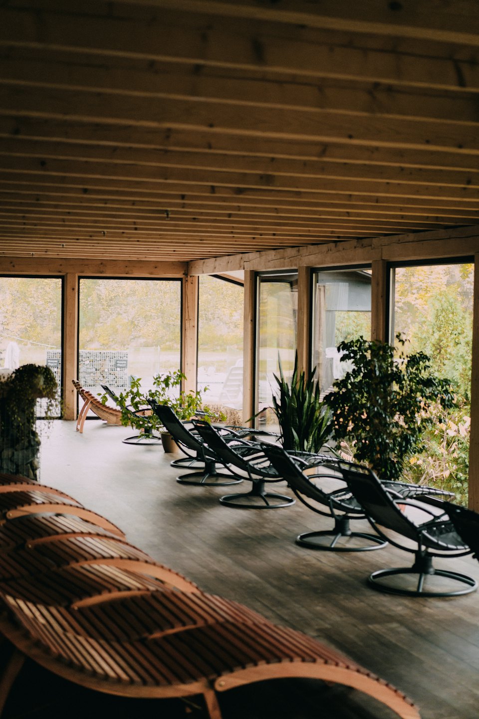Moderne loungestoelen staan onder houten balken bij grote ramen.