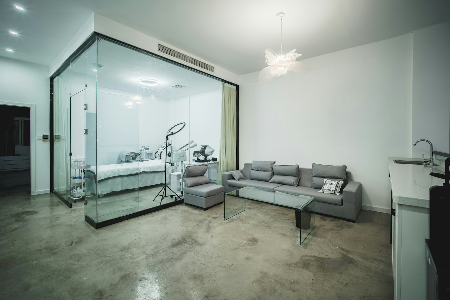 Moderne spa-wachtruimte en behandelkamer met wit bed.